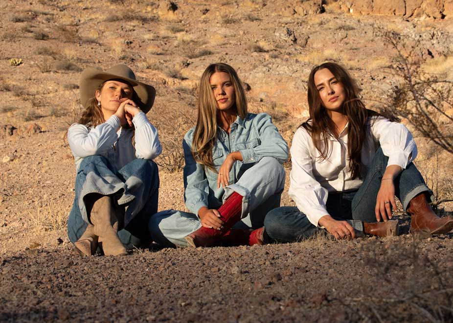 Three women sitting in the desert wearing Hyer boots